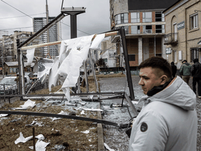 People stand near a damaged structure caused by a rocket on February 24, 2022 in Kyiv, Ukraine.