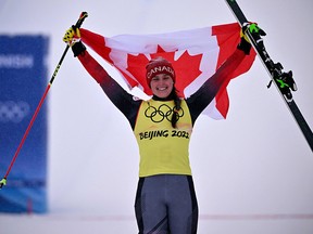 Silver medallist Canada's Marielle Thompson holds the flag on the podium during the venue ceremony after the freestyle skiing women's ski cross big final during the Beijing 2022 Winter Olympic Games.