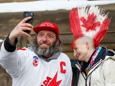 A man takes a selfie with a woman sporting a Canada-flag mohawk as truckers and supporters continue to protest vaccine mandates and other COVID measures in downtown Ottawa on Feb. 9, 2022.