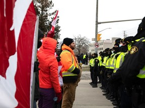 Protesters confront police officers as they move to clear a blockade at the Ambassador Bridge that connects Windsor with Detroit, on Saturday, Feb. 12, 2022.
