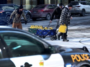 Feb 14, 2022 - Truckers occupation and protesting continues its 18th day in downtown Ottawa Sunday afternoon. Three men take full cans of fuel past the police on O' Connor Street in Ottawa Monday morning.  TONY CALDWELL, Postmedia.