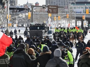 Eine Polizeikette, unterstützt von einer berittenen Einheit und einem schweren gepanzerten Fahrzeug, rückt am 18. Februar 2022 in Ottawa auf Demonstranten vor.