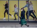 Ein Fußgänger mit Maske geht an einem Wandbild einer Familie vorbei, die während der COVID-19-Pandemie am Donnerstag, dem 3. Februar 2022, einen gemütlichen masselosen Spaziergang in Toronto genießt.