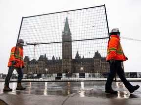 Workers carry a piece of fencing to shore up existing barricades on Parliament Hill, on the 21st day of the Freedom Convoy protest against COVID-19 measures that has grown into a broader anti-government protest in Ottawa, on Feb. 17, 2022.