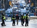 Ein Demonstrant, der einen leeren Kraftstoffbehälter auf einem Besenstiel trägt, geht an Polizeibeamten der Provinz Ontario vorbei, als Protest gegen die COVID-19-Beschränkungen, die durch Verkehrsinfarkte und das Geräusch von LKW-Hupen gekennzeichnet waren, bis in die zweite Woche in Ottawa am Montag, 2. Februar, andauern. 7, 2022. DIE KANADISCHE PRESSE/Justin Tang