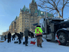 Protesters in Ottawa, including at least one child, shovel snow to form a barrier around a truck, February 18, 2022.