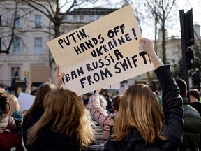 Demonstrators hold a placard calling on Russia to be banned from the Swift banking system as they attend a protest rally outside of the Russian Embassy in London, on February 26, 2022.