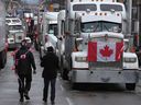 Protesters walk between trucks parked along Wellington Street in downtown Ottawa as the 