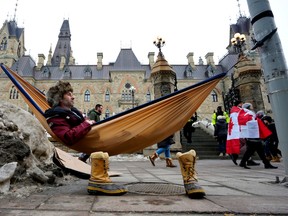 A man sits in a hammock outside the West Block on Parliament Hill in Ottawa, on Feb. 11.