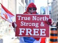 A supporter of the Freedom Convoy holds up a "True North Strong and Free" sign in downtown Ottawa on Feb. 5, 2022. The protesting truckers are modern-day freedom fighters, writes Frank Stronach.