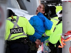 A protester yells "hold the line" while being taken away under arrest as police take action to put an end to a protest, which started in opposition to mandatory COVID-19 vaccine mandates and grew into a broader anti-government demonstration and occupation, in Ottawa, Friday, Feb. 18, 2022.
