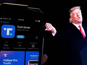 Photo illustration of former President Donald Trump next to a phone screen that is displaying the Truth Social app. (Photo by Stefani Reynolds / AFP)