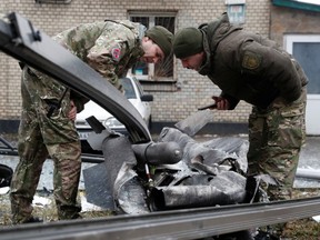 Police officers inspect the remains of a missile that fell in the street in Kyiv, Ukraine, February 24, 2022.