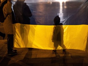 The shadow of a boy is seen projected on a Ukrainian national flag as people gather to protest after Moscow's decision to formally recognize two Russian-backed regions of eastern Ukraine as independent at the industrial city of Mariupol, located about 20 kilometers from the rebel-controlled areas in eastern Ukraine, February 22, 2022. REUTERS/Carlos Barria