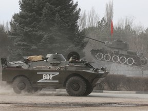A Russian army vehicle drives past a monument displaying a Soviet-era tank, in the town of Armyansk, Crimea, on Feb. 24.