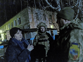 Ukrainische Soldaten sprechen am 17. Februar 2022 in Stanytsia Luhanska, Ukraine, mit einem Anwohner außerhalb eines Kindergartens, der nach Angaben von Militärbeamten durch Beschuss beschädigt wurde.