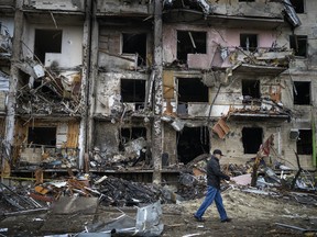 A man walks past a building damaged following a rocket attack the city of Kyiv, Ukraine, Friday, Feb. 25, 2022. (AP Photo/Emilio Morenatti)