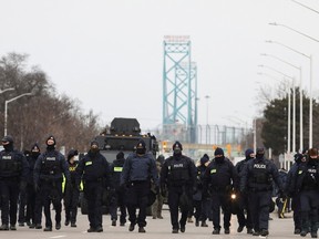 Police officers move along a road leading to the Ambassador Bridge, which connects Detroit and Windsor, after clearing demonstrators, during a protest against coronavirus disease (COVID-19) vaccine mandates, in Windsor, Ontario, Canada February 13, 2022. REUTERS/Carlos Osorio