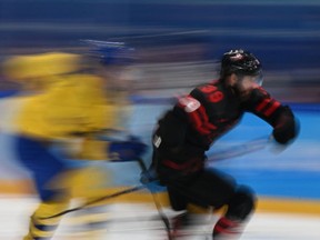 Suecia (en azul y amarillo) y canadienses patinan durante los cuartos de final masculinos del torneo de hockey sobre hielo en los Juegos Olímpicos de Invierno de Beijing 2022.