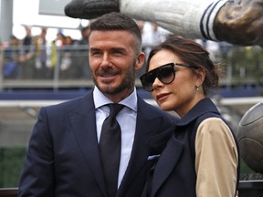 David Beckham and his wife Victoria Beckham pose for a photo with his statue at Dignity Health Sports Park on March 2, 2019 in Carson, California.