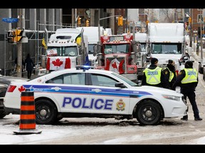 Police patrol a barricade while vehicles block downtown streets as truckers and supporters protest COVID-19 vaccine mandates, in Ottawa, February 3, 2022.