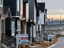 Angebaute Häuser zum Verkauf in der Gemeinde Livingstone vor der fernen Skyline von Calgary.