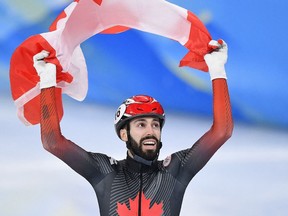 Steven Dubois of Canada celebrates with the national flag of Canada after winning silver in a nail biter.