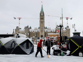A demonstrator clears snow from around a shelter as truckers and supporters continue to protest COVID-19 mandates in Ottawa on Feb. 3, 2022.