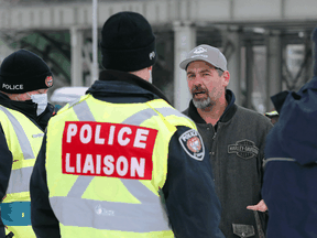 Truckers and supporters talk with police liaison officers as they continue to protest COVID-19 mandates, February 4, 2022. Late this week, the convoy organizers welcomed a disgruntled RCMP corporal to their ranks.