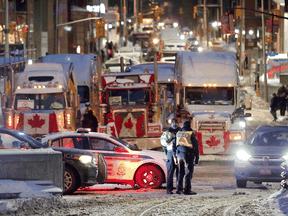 Police officers stand in front of trucks as truckers and supporters continue to protest COVID-19 restrictions in Ottawa, February 4, 2022.