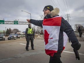 Protesters yell at police as they attempt to clear the anti-mandate blockade of the Ambassador Bridge on Huron Church Road, on Saturday, February 12, 2022.