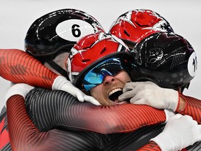 Canada team members celebrate after winning the final A of the men's 5000m relay short track speed skating event during the Beijing 2022 Winter Olympic Games.