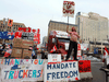 People stand in front of trucks blocking a downtown street as truckers and their supporters protest against COVID-19 restrictions in Ottawa, February 16, 2022.