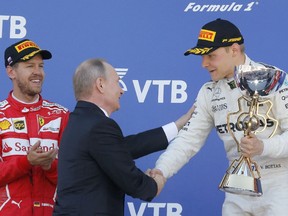 Wladimir Putin gratuliert dem Sieger und Mercedes-Formel-1-Fahrer Valtteri Bottas aus Finnland, während der zweitplatzierte Ferrari-Formel-1-Fahrer Sebastian Vettel aus Deutschland in Sotschi 2017 in der Nähe auf dem Podium steht.