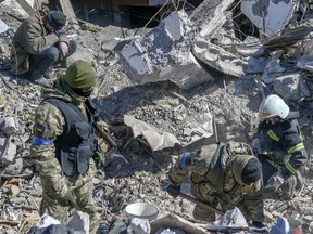 Ukrainische Soldaten und Rettungskräfte suchen nach Leichen in den Trümmern der am Tag zuvor von russischen Raketen getroffenen Militärschule in Mykolajiw in der Südukraine.