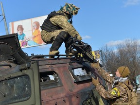 A Ukrainian Territorial Defence fighter takes the automatic grenade launcher from a destroyed Russian infantry mobility vehicle, after a fight in Kharkiv, Ukraine, on Feb. 27.