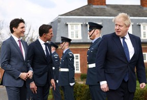 Prime Minister Justin Trudeau, Dutch Prime Minister Mark Rutte, and British Prime Minister Boris Johnson review the Royal Air Force (RAF) troops following a meeting at the RAF base in Northolt, near London, on March 7, 2022.