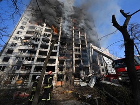 Firefighters extinguish a fire in a 16-storey residential building in Kyiv on March 15, 2022, after strikes on residential areas killed at least two people.