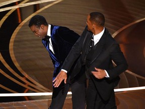 Will Smith, right, slaps actor and comedian Chris Rock onstage during the 94th Oscars in Hollywood, Calif., on March 27, 2022, after Rock made a joke about the medical condition that has caused Jada Pinkett Smith to lose her hair.