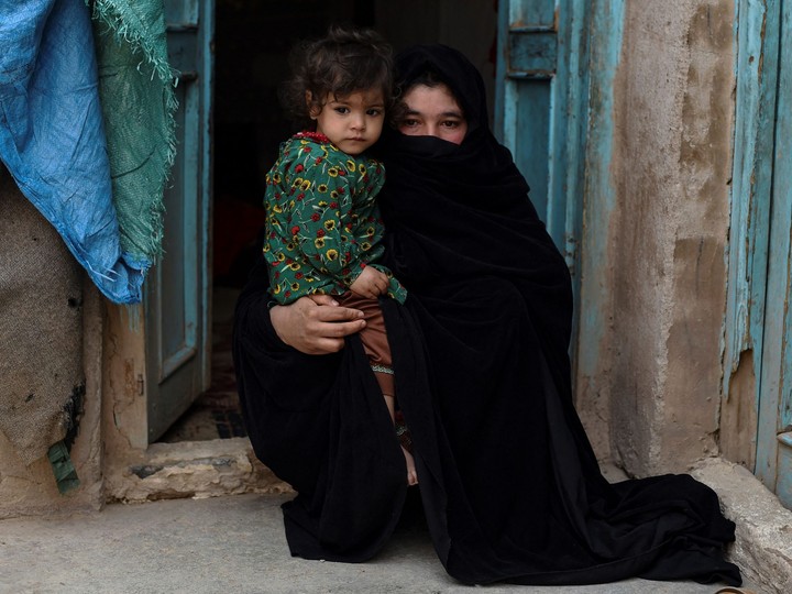  In this photo taken on Feb. 3, 2022, Aziza, who plans to sell her kidney to raise money for her family, poses with her young daughter Parwina at their house in Herat.