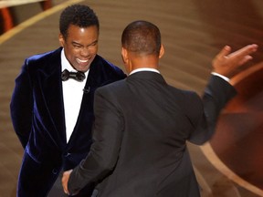 Will Smith (R) swings to strike Chris Rock on stage during the 94th Academy Awards in Hollywood, Los Angeles, California, U.S., March 27, 2022.