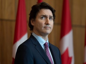 Premierminister Justin Trudeau sieht auf einer riesigen Leinwand zu, wie Sean Fraser, Minister für Einwanderung, Flüchtlinge und Staatsbürgerschaft, während einer Pressekonferenz am Freitag, den 25. Februar 2022 in Ottawa per Video spricht.