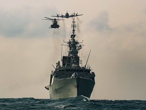 A CH-148 Cyclone helicopter and a CP-140 Aurora maritime patrol aircraft fly over the Royal Canadian Navy frigate HMCS Winnipeg during an exercise in the Asia-Pacific region in 2020.