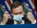 Albertas Premier Jason Kenney nimmt seine Maske ab, als er in Calgary ein Februar-COVID-19-Update gibt.