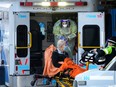 Paramedics transfer a patient out of their ambulance to the emergency department at Michael Garron Hospital during the COVID-19 pandemic in Toronto on Monday, January 10, 2022.