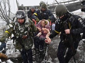 Ukrainian soldiers help an elderly woman across a destroyed bridge as she evacuates from the city of Irpin, northwest of Kyiv, on March 8, 2022. More than two million people have fled Ukraine since Russia launched its full-scale invasion less than two weeks ago, the United Nations said on March 8.