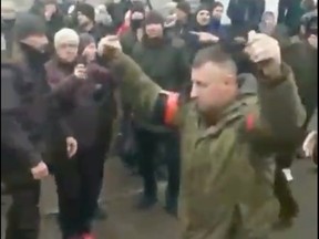 A video shows a Russian soldier holding up two grenades as he walks by Ukrainians in the town of Konotop.