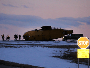 Emergency crews work around the wreckage of a downed CH-149 Cormorant search and rescue helicopter at 9 Wing Canadian Forces Base Gander, in Gander, N.L., March 10, 2022.