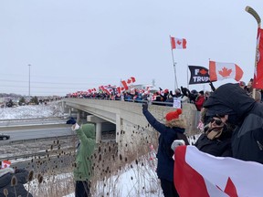 Supporters line the Wellington Road overpass on Highway 401 to cheer on vehicles heading to January's "Freedom Convoy" protest in Ottawa. Protesters will take to the 401 and 402 Saturday as part of a Canada-wide protest. (Dale Carruthers/The London Free Press)