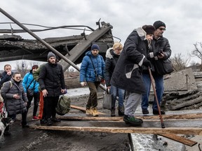 Residents of Irpin flee heavy fighting via a destroyed bridge as Russian forces entered the city on March 07, 2022 in Irpin, Ukraine.